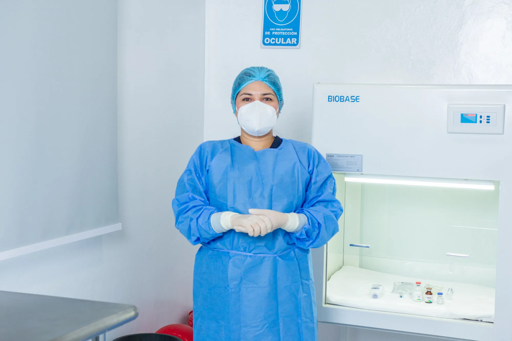 Personal de OncoCare con equipo de protección junto a la cabina de seguridad biológica